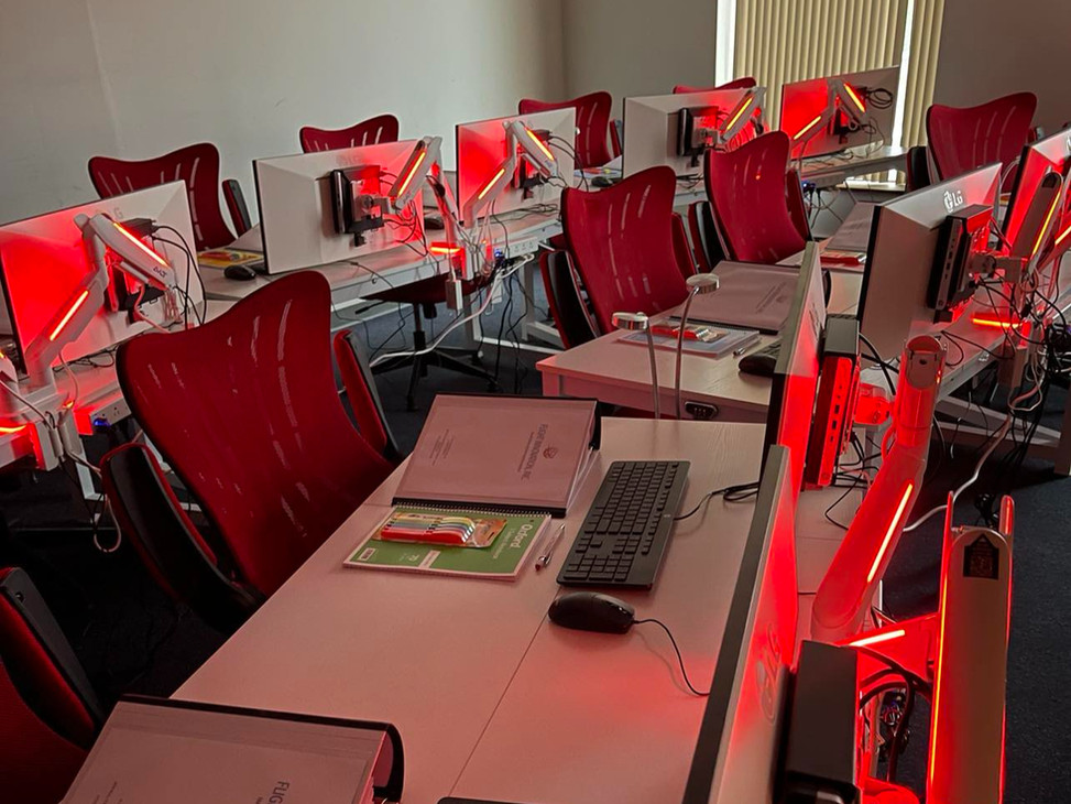 Reference materials and computer monitors at a Flight Innovation classroom desk