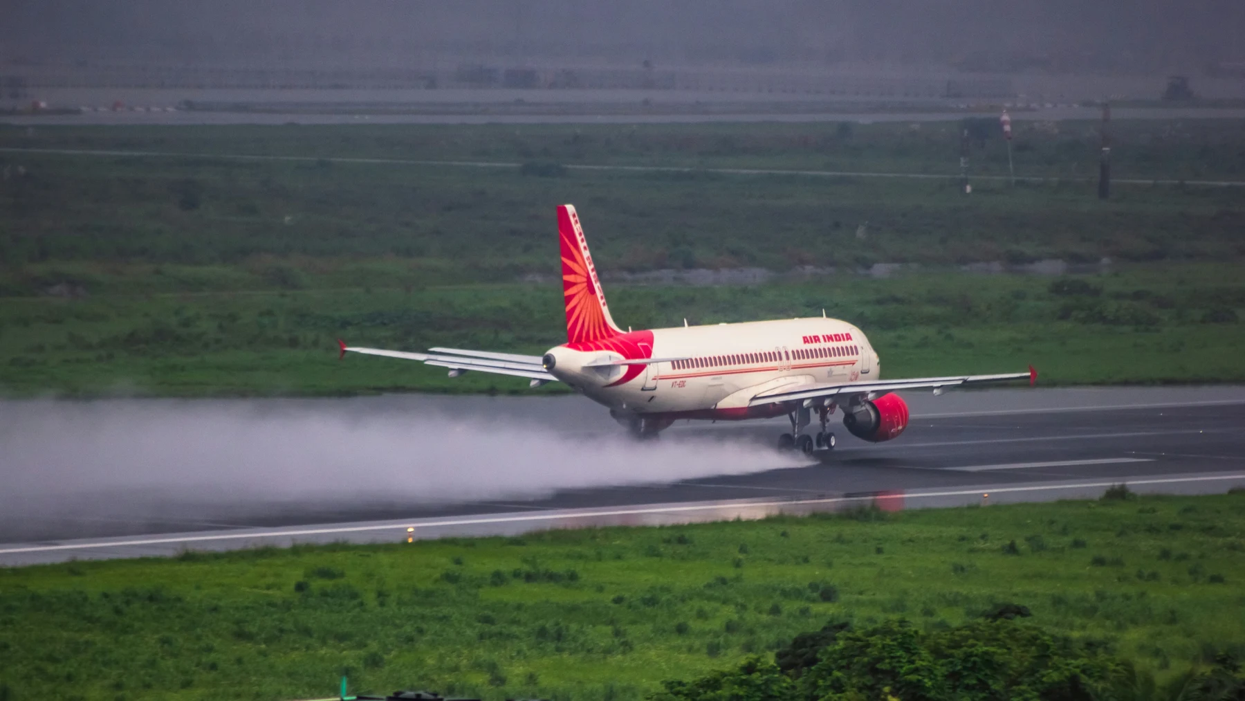 Airplane taking off, creating a dramatic spray on the wet runway.